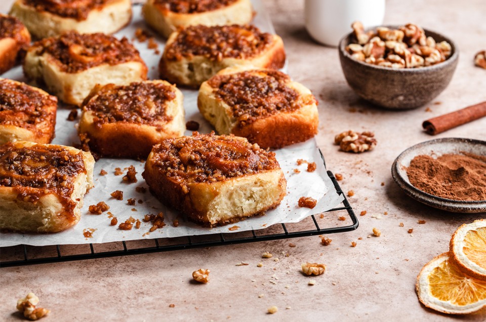 A tray of orange sticky rolls topped with walnuts - select to zoom