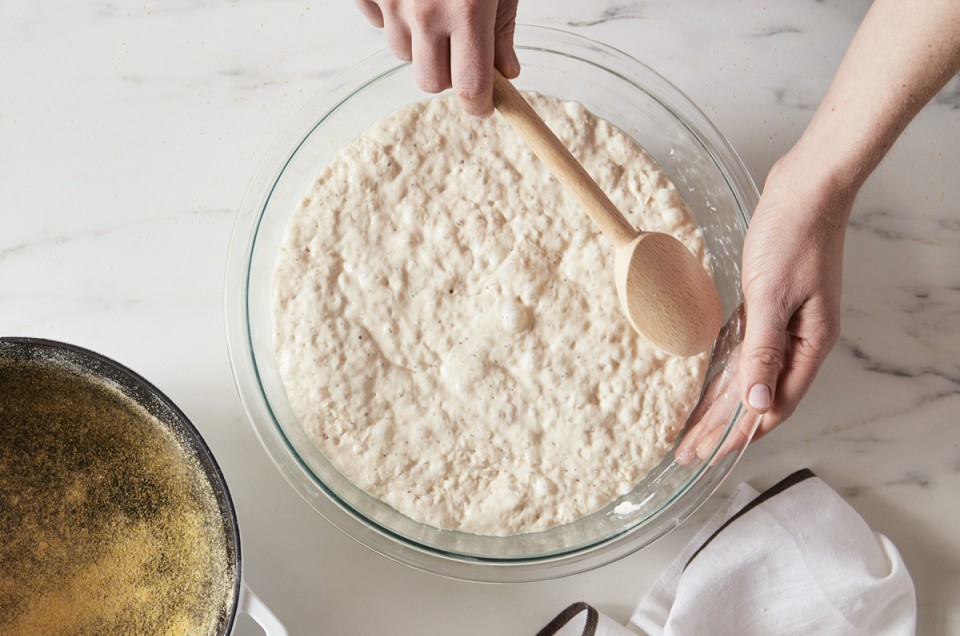 Proofed bread dough, with lots of bubbles, in a glass bowl after an overnight rise