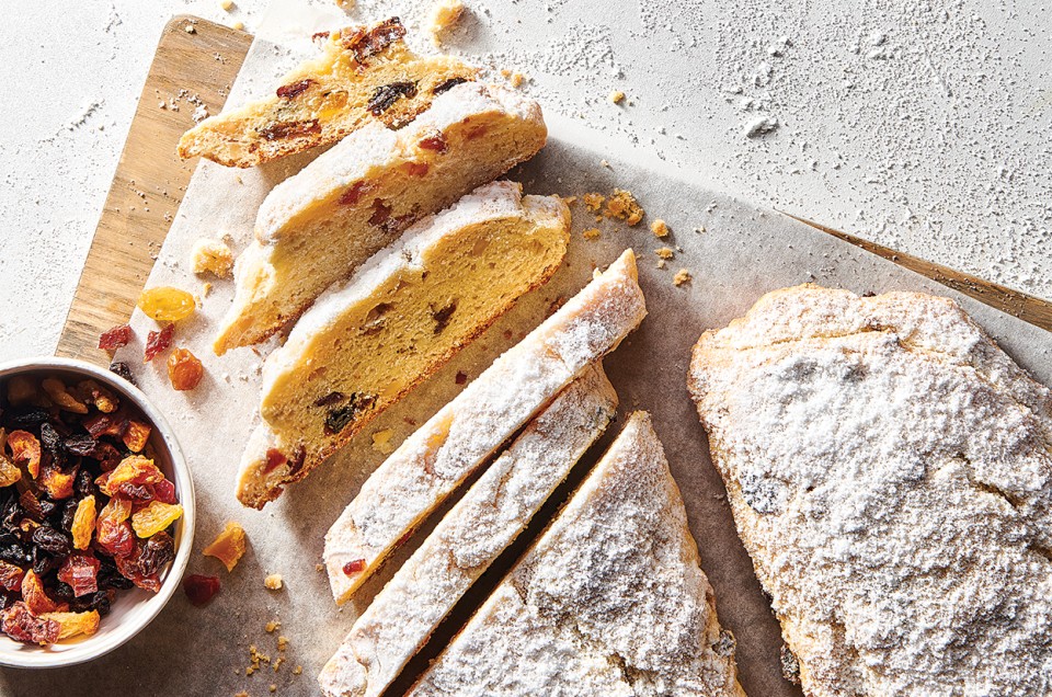 Our Easiest Stollen on a cutting board with dried fruit mix and sliced into pieces - select to zoom
