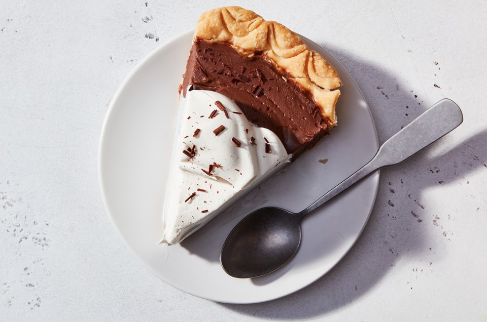 A slice of Chocolate Cream Pie on a plate, topped with whipped cream and chocolate shavings - select to zoom