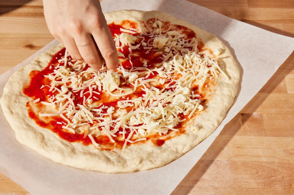 Topping unbaked pizza with shredded cheese