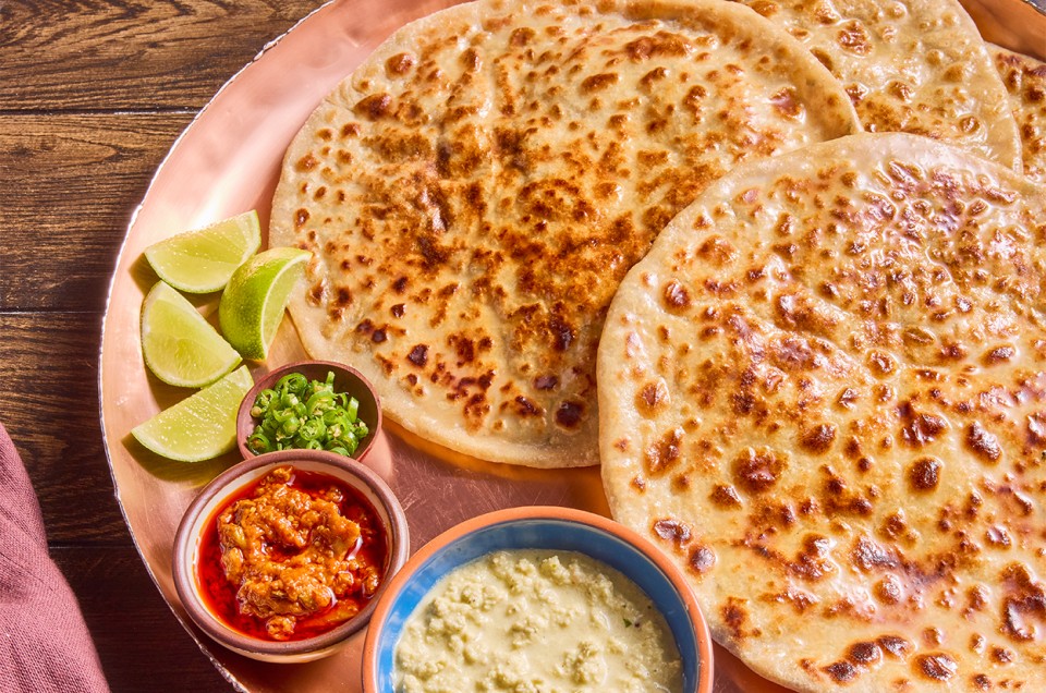 Aloo Paratha (Spiced Potato-Stuffed Flatbread) on a serving plate with lime - select to zoom