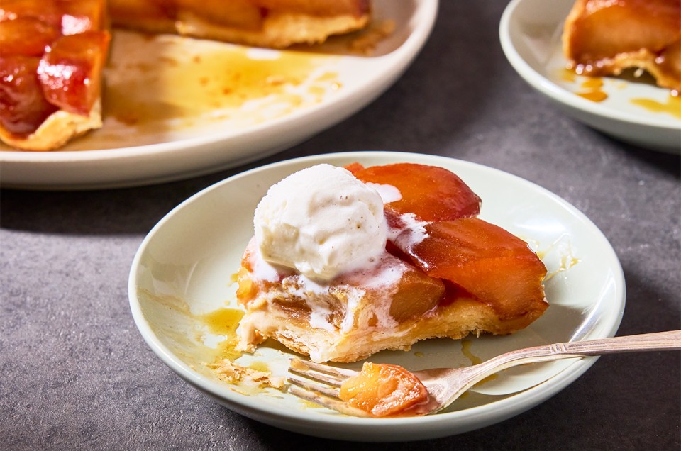 A slice of Classic Apple Tarte Tatin on a plate with a scoop of vanilla ice cream on top - select to zoom