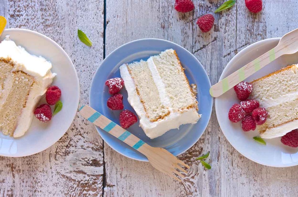 Three slices of Tender White Cake on plates, revealing their double layers of white cake and vanilla frosting. - select to zoom