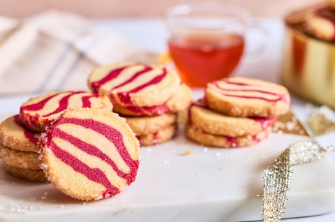 A counter-level view of striped peppermint shortbread cookies showing the scale and shape of the cookie. - select to zoom