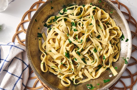 A bowl of gluten free pasta dressed with parmesan and parsley. - select to zoom