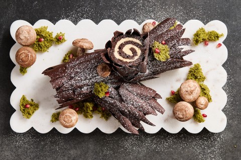 Chocolate Buche de Noel with Cookie Butter Whipped Ganache showing beautiful layers of chocolate coated cake and edible decorations in the style of a log. - select to zoom