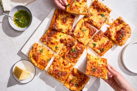 A sliced up Flaky Puff Crust Pizza with pieces being taken out - select to zoom