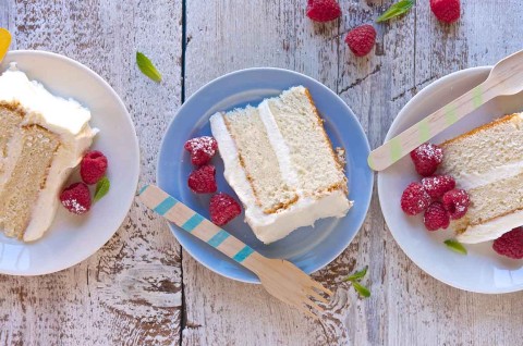Three slices of Tender White Cake on plates, revealing their double layers of white cake and vanilla frosting. - select to zoom