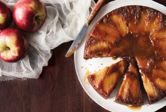 A freshly baked Apple Upside-Down Cake, inverted onto a serving platter with a slice removed.