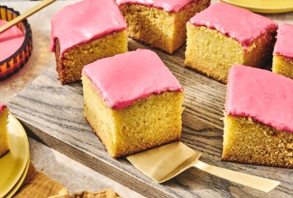 Cranberry-Orange Olive Oil Cake sliced up and arranged on a glass plate with a gold hued serving spatula under one of the golden slices.