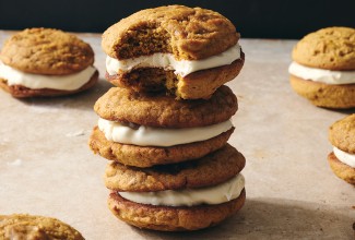 Pumpkin Whoopie Pies photographed in a stack on a counter showing the layers of pumpkin cookie and creamy filling.