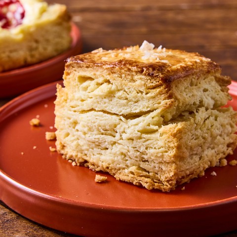 Side view of a tall ultimate flaky biscuit that clearly shows horizontal layers in the biscuit, a perfect golden baked exterior, and a bit of salt on top.