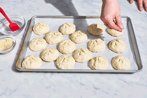 Topping gluten-free roll dough with seeds before baking.