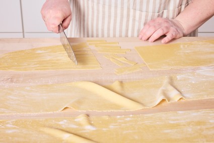 Slicing homemade egg noodle dough 