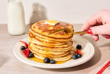 Easy Buttermilk Pancakes topped with maple syrup on a plate with fresh fruit