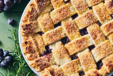 Concord Grape Pie photographed from above showing a lovely woven pie crust on top with brown hues and coarse sugar.