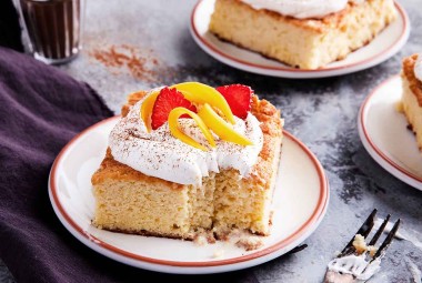 A slice of Tres Leches Cake topped with whipped cream on a plate